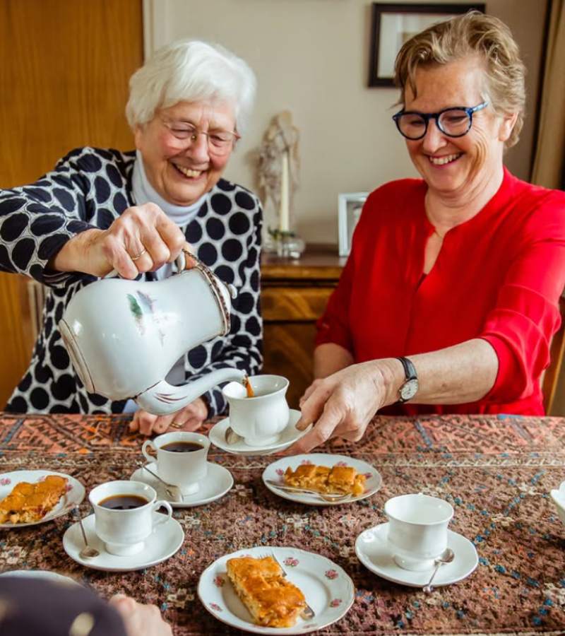 Oma en dochter drinken thee en eten appeltaart